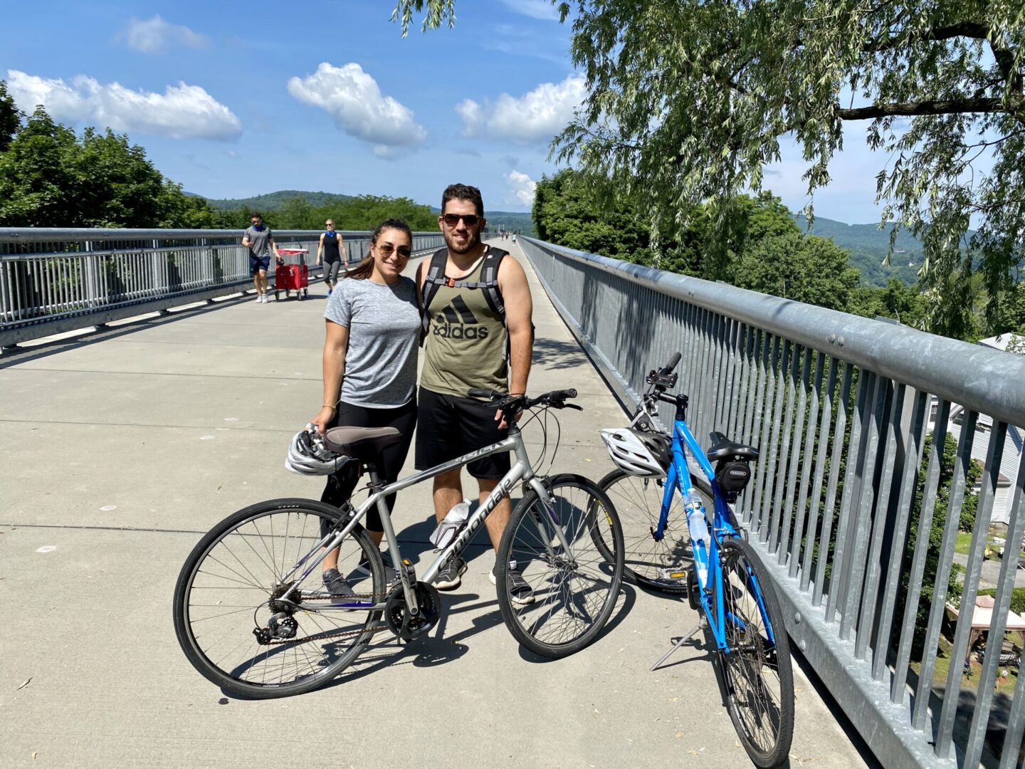 Two people standing next to a bike on the side of a bridge.
